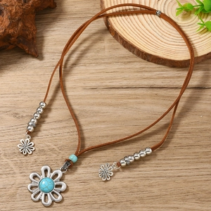 Detail of bohemian leather necklace featuring silver flower pendant and turquoise stone