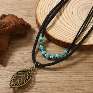 Detail of bohemian turquoise beaded necklace and vintage bronze leaf pendant on wood