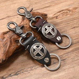Vintage punk leather keychain with cross alloy badge and antique hardware on wood