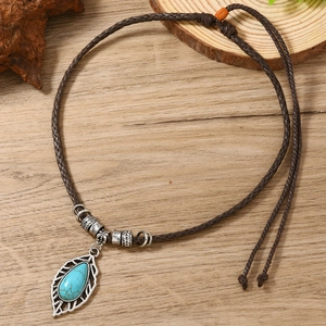 Détail du pendentif feuille bohème avec pierre turquoise sur cordon tressé marron foncé