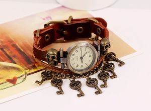 Detail of vintage leather bracelet watch with bronze skull studs and key charms
