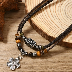 Détail du pendentif fleur vintage sur cordon tissé marron avec billes en bois rustique
