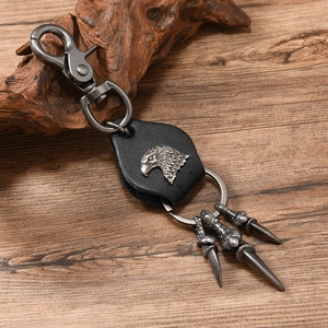 Detail of punk eagle pendant keychain with leather base and claw charms on wood background