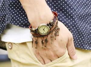 Detail of vintage leather bracelet watch with bronze charms on a person's wrist