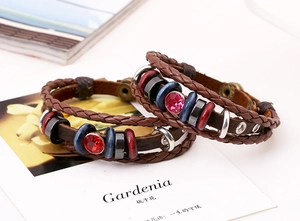 Dettaglio di bracciali bohémien in pelle intrecciata con perline e cristallo rosso