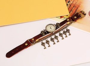 Detail of vintage leather watch with bronze keys, skull charms and roman numerals dial