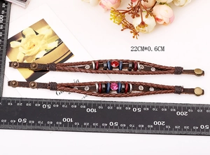Dettaglio di braccialetti retrò in pelle intrecciata con perle di ceramica e fibbia