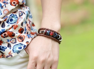 Dettaglio del bracciale in pelle intrecciata con gemma rossa e perline di legno
