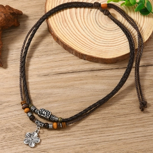 Détail du collier vintage en cuir tressé avec pendentif fleur d'argent et perles de bois