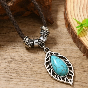 Détail du pendentif feuille turquoise bohème avec cadre argenté sur fond bois