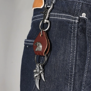 Vintage punk style eagle pendant keychain with brown leather on blue jeans