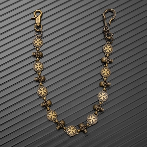 Detail of vintage bronze skull and maltese cross biker chain on textured black background