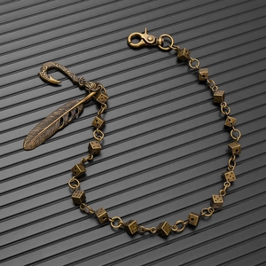 Close-up of vintage bronze wallet chain with metal dice, feather and fish hook charms