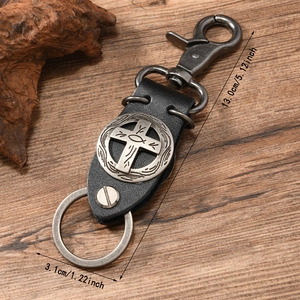 Punk style cross leather keychain with vintage silver emblem on rustic wood background