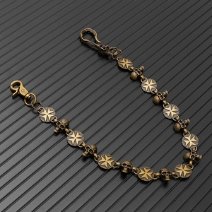 Close-up of vintage bronze skull chain with cross-engraved metal links for bikers