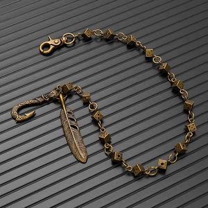 Detail view of retro bronze dice pants chain with feather pendant and punk metal hooks