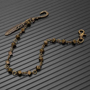 Detail of vintage bronze dice chain with carved feather charm and industrial spring clasp
