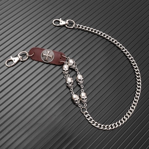 Detail of punk style skull charms and leather patch on silver metal trouser chain