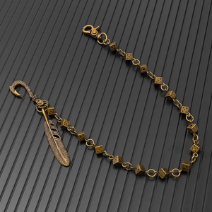 Detail of vintage metal dice chain with bronze feather pendant and engraved clasp