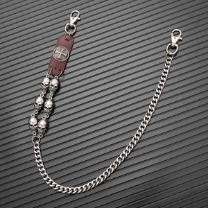 Detail view of punk skull trouser chain with leather cross patch and silver metal links