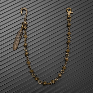 Detail of vintage bronze waist chain featuring metal dice links and a feather pendant