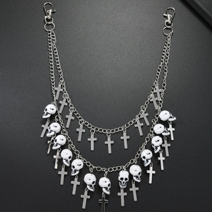 Detail view of punk style double-layered chain with skull and cross charms on grey background