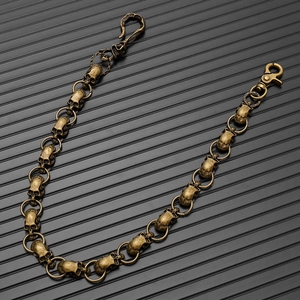 Close-up of vintage bronze skull chain with lobster clasp and retro metallic texture