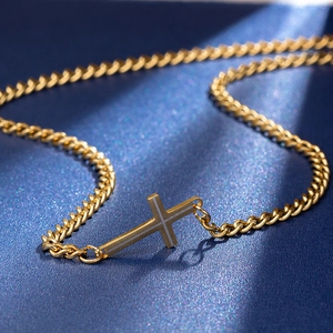 Golden sideways cross pendant on cuban chain necklace over deep blue background