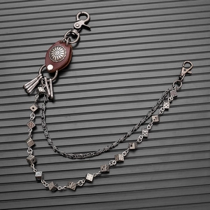 Detail of punk style double-layer waist chain with metal dice charms and brown leather trim