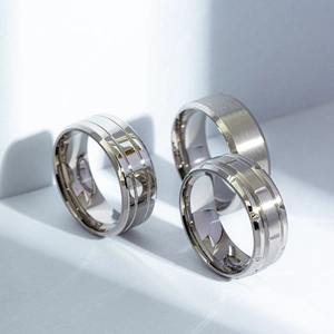 Three men's matte and polished silver titanium steel rings with textured industrial designs