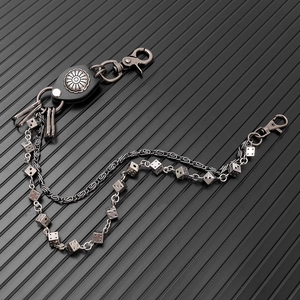 Detail of double punk waist chain with metal dice charms and black leather attachment