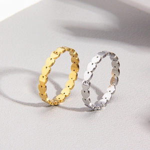 Dettaglio di anelli a cuore infinito in acciaio al titanio lucido oro e argento