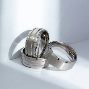 Detail of three men's black matte and silver steel rings with brushed finish and engraving