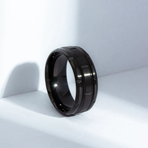 Detail of matte black titanium steel ring with industrial geometric textures and grooves
