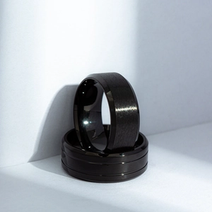 Detail view of two matte black titanium rings with brushed finish and polished beveled edges