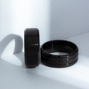 Detail of matte brushed and polished black titanium steel rings for men on white background