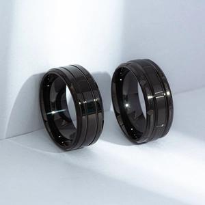 Detail of matte black titanium rings featuring double grooves and faceted surface design