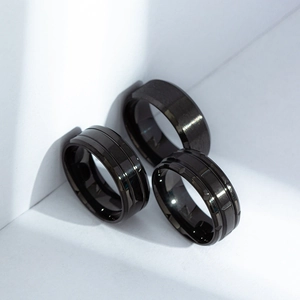Detailed view of three matte black stainless steel rings with brushed finish and grooves