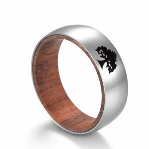 Détail macro d'une bague en acier titane avec silhouette d'arbre noir et bois de rose