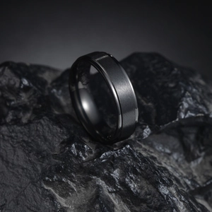6mm matte black titanium steel ring with brushed surface on textured stone background