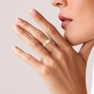 Wide gold stainless steel ring with white circular patterns worn on a hand