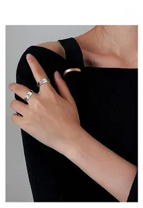 Detail view of engraved rotating spinner rings in silver steel worn by a fashion model