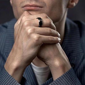 Nahaufnahme eines gebürsteten schwarzen Titanstahlrings an einem männlichen Model im Anzug