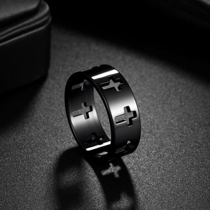 Matte black titanium cross cutout ring for men with decorative shadows on dark surface