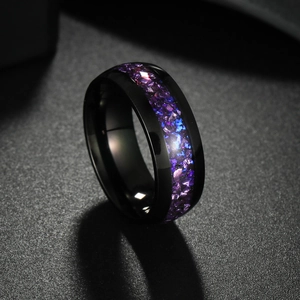 Détail macro d'une bague noire polie avec incrustation de pierres violettes et bleues