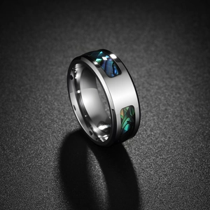 Bague en acier inoxydable poli avec incrustation d'abalone segmentée sur fond texturé gris