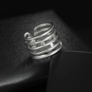 Minimalistischer silberner mehrlagiger offener Ring mit Punktstruktur auf Lederhintergrund
