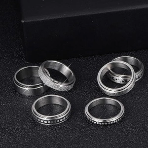 Set of six silver stainless steel spinner rings with star and moon relief textures