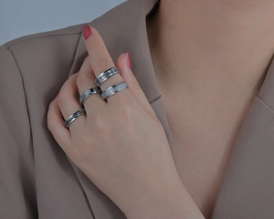 Detail view of silver spinning rings featuring floral relief and matte texture on fingers