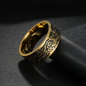 Detail of vintage golden Viking evil eye ring with black engraved totems on titanium steel